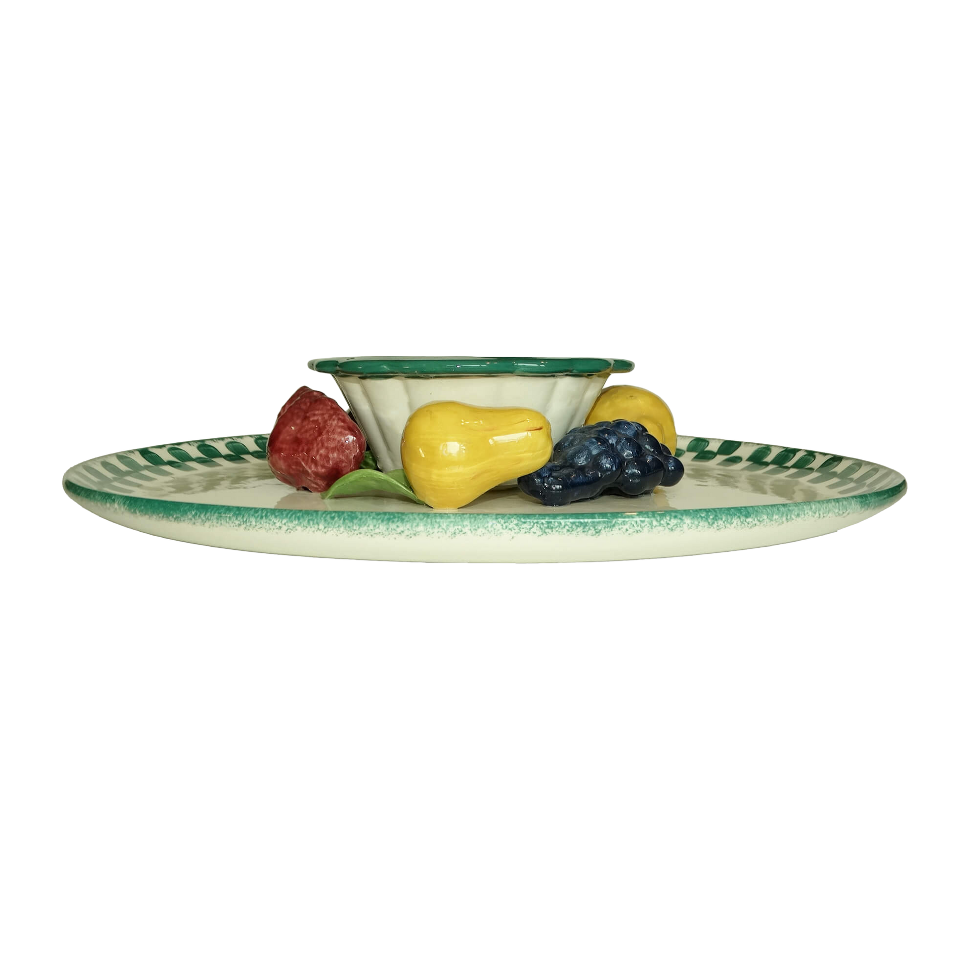Ceramic plate with decorative edge holding small ceramic fruits on a white background