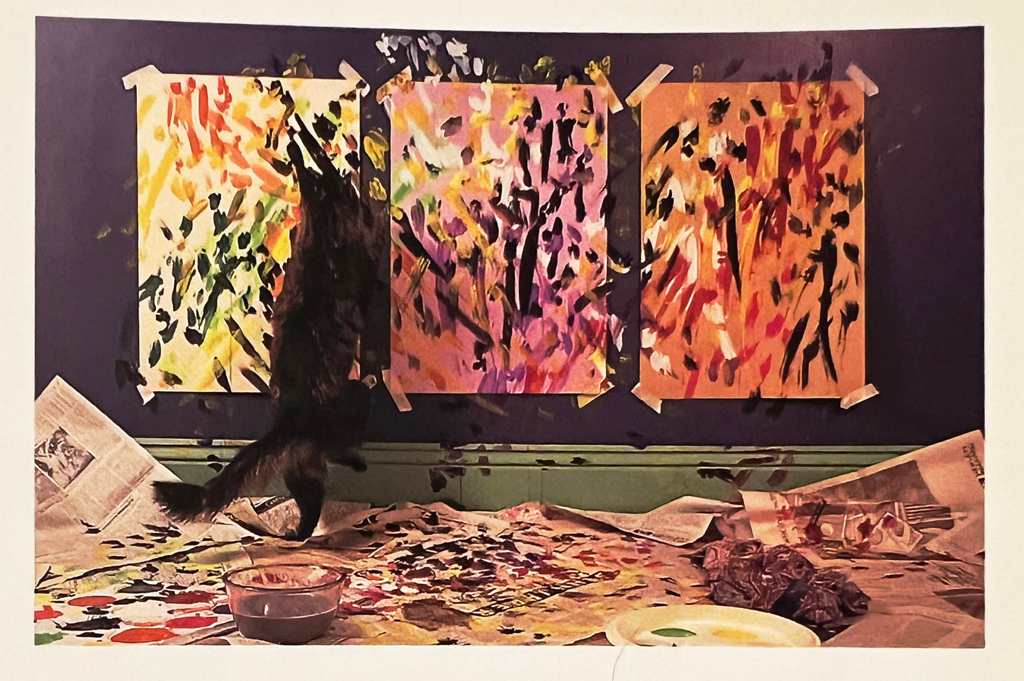 Artistic setup with abstract paintings and a cat interacting with the art supplies.