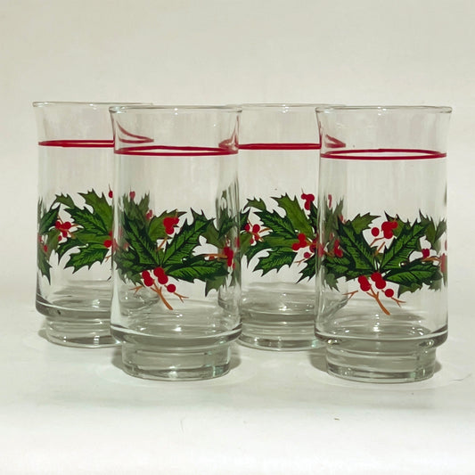 Set of four glass tumblers with holly design on a white background