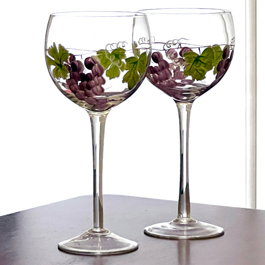 Two wine glasses with grape design on a white background