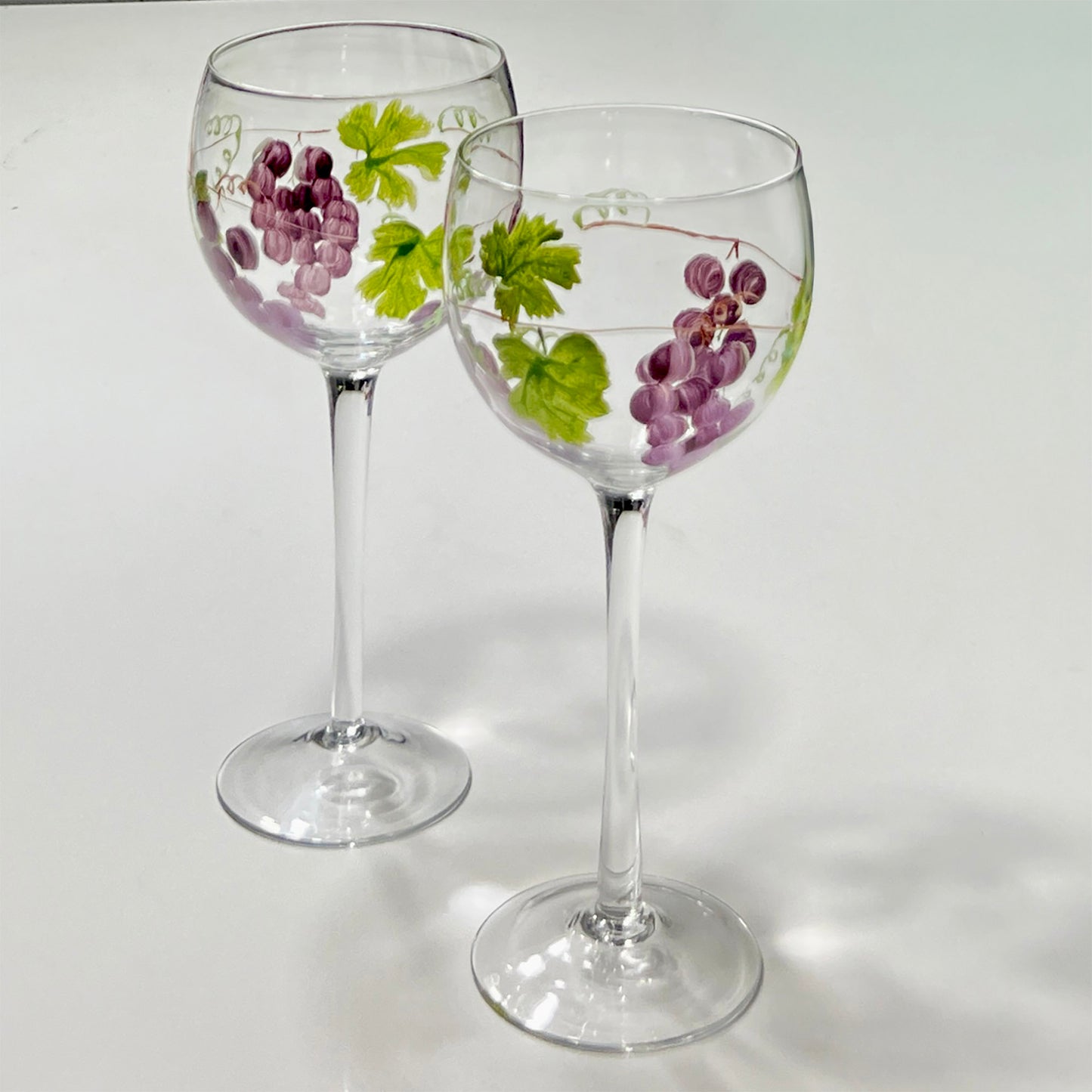 Two wine glasses with grapevine designs on a white background