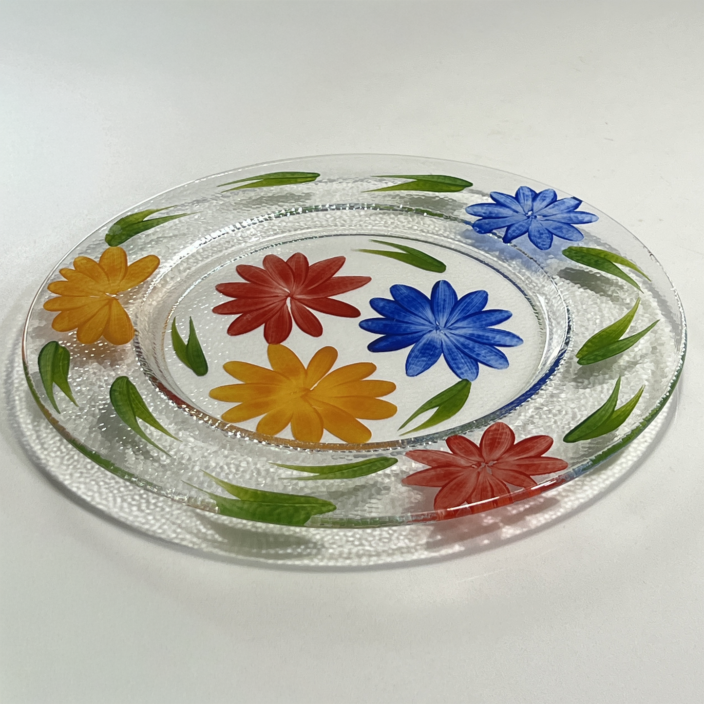Clear glass plate with colorful floral designs on a white background