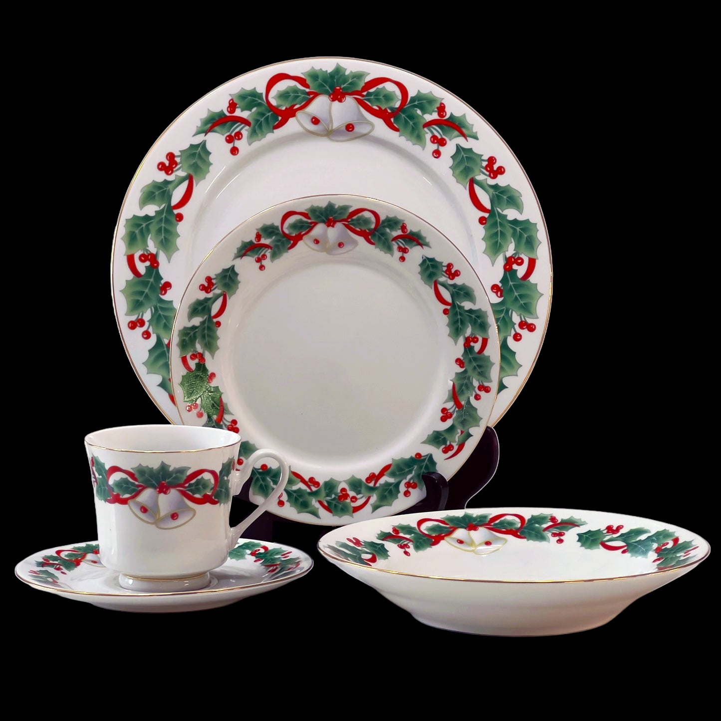 Christmas-themed dinnerware set with holly design on a black background