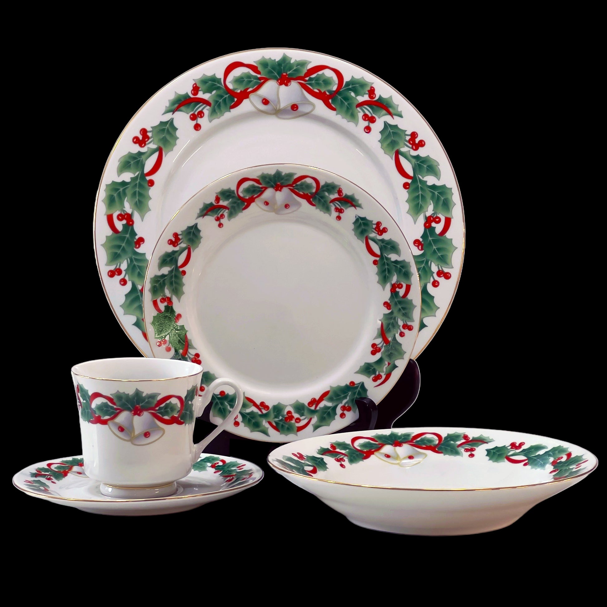 Christmas-themed dinnerware set with holly design on a black background