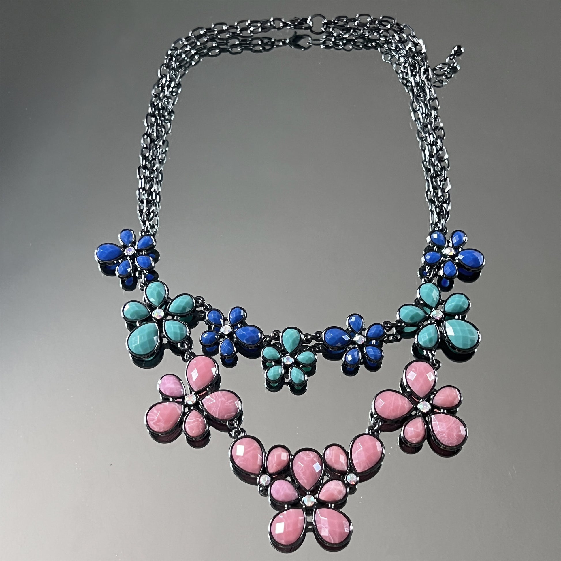 Necklace with floral designs in blue, pink, and teal on a gray background