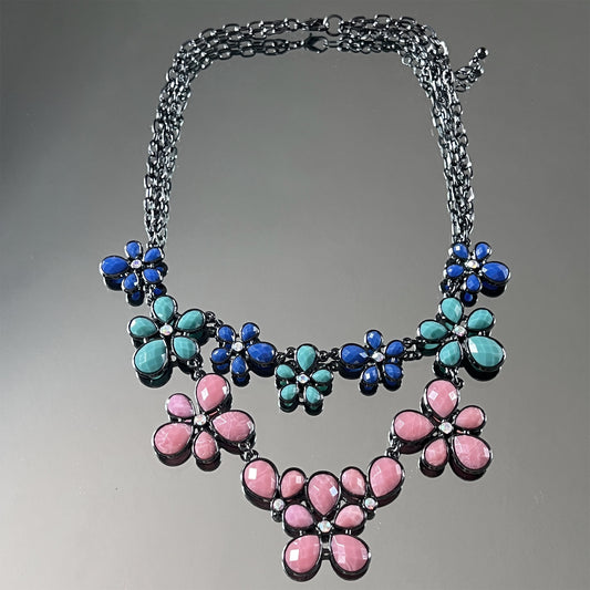 Necklace with floral designs in blue, pink, and teal on a gray background