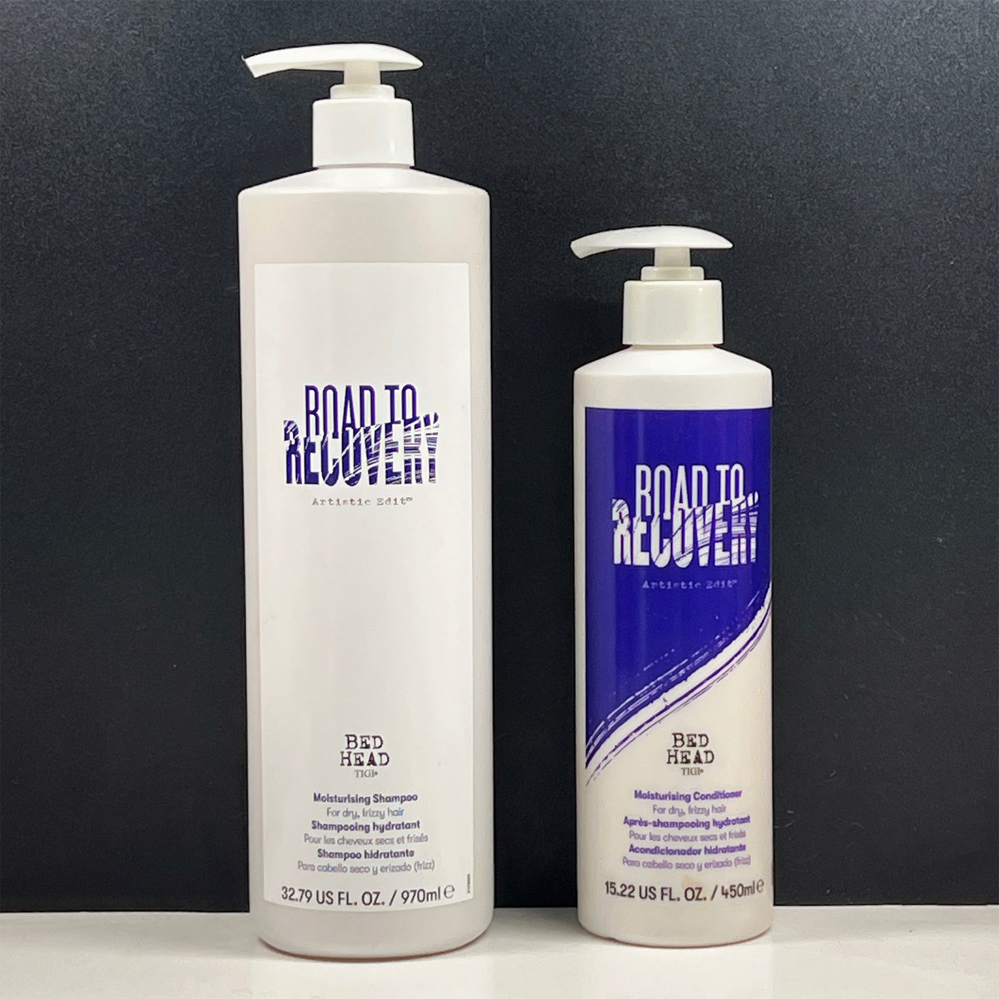 Two bottles of Bed Head Road to Recovery hair care products on a black background