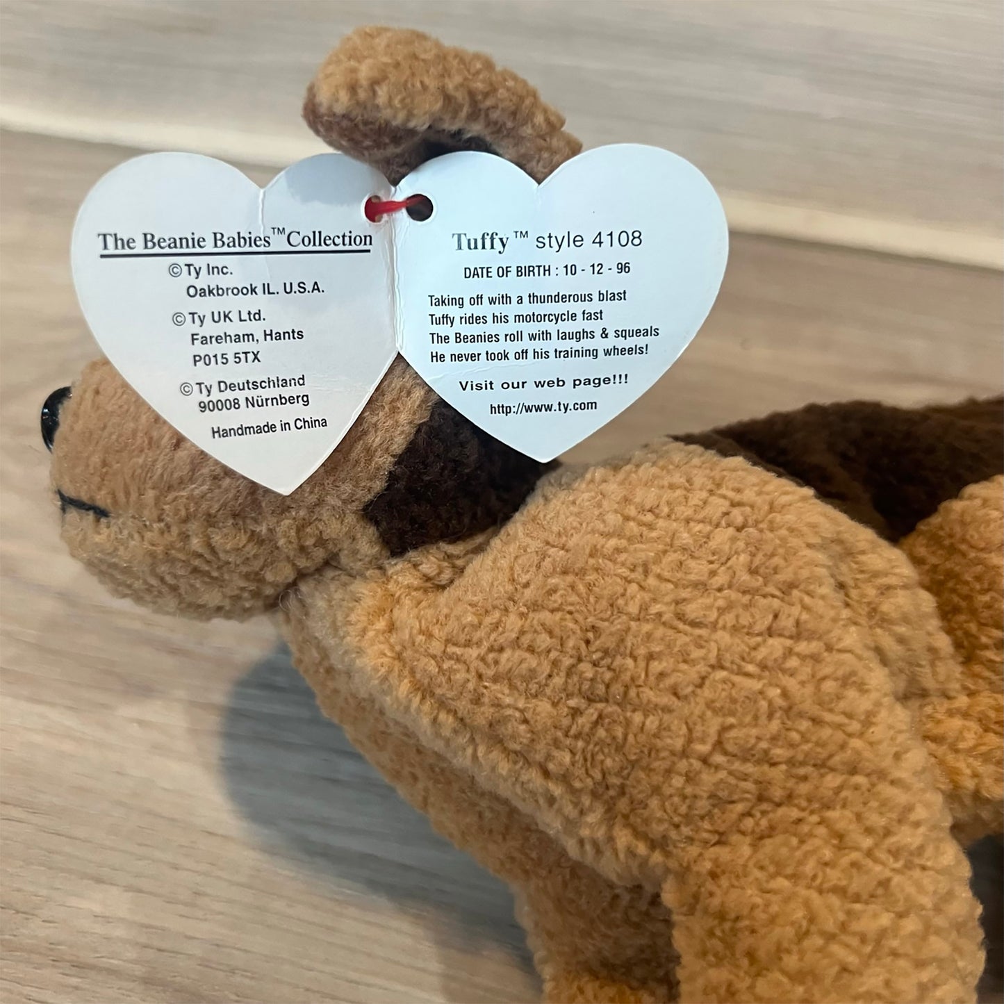 Plush dog toy with heart-shaped tags on a wooden surface