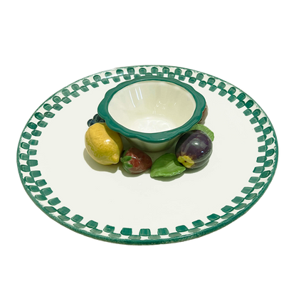 Ceramic plate with green rim and decorative edge, featuring a small bowl and fruit figurines on a white background.