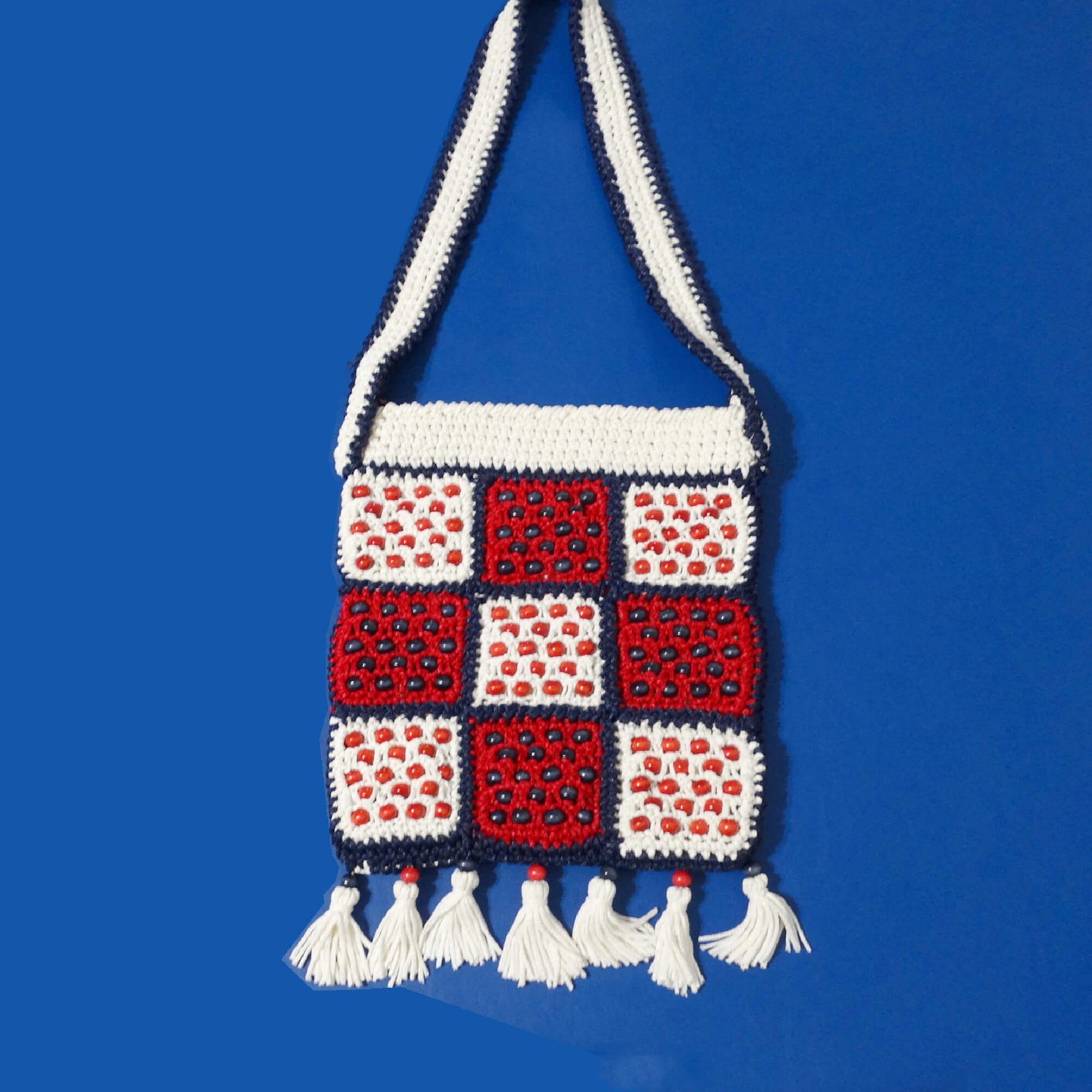  Walborg-Red,-White-Navy-Blue-Beaded-Macrame-Shoulder-Bag-Laying-Flat against blue-background.